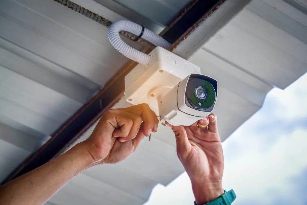 A man installs a security camera on the roof