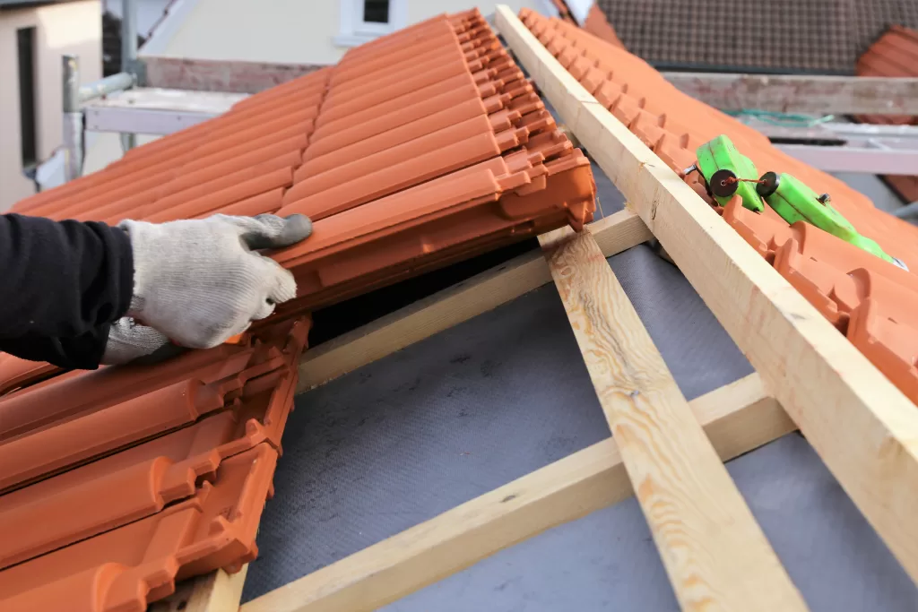 The roofer expertly lays out tiles, carefully arranging and positioning them on the roof surface