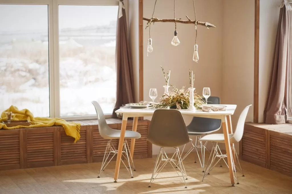 Large vinyl windows allow natural light into a kitchen with dishes and silverware on the table