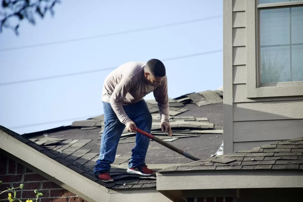 A handyman removes shingles from a client's roof
