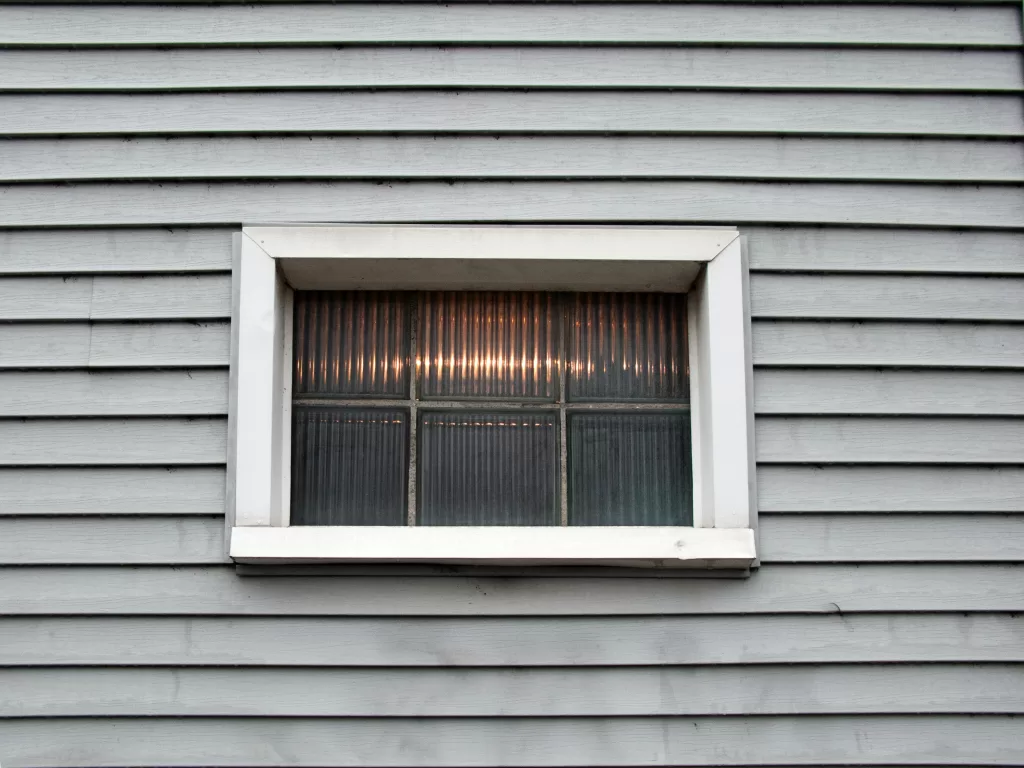 A window and wonderfully laid white-colored siding