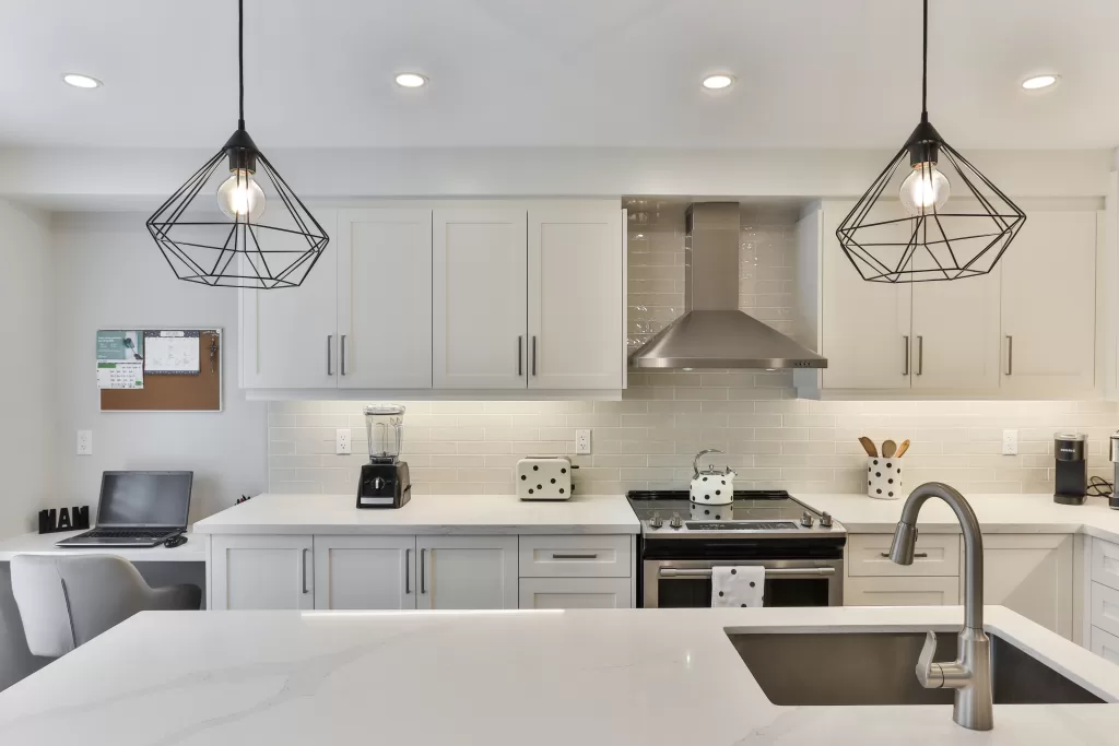 A spacious white kitchen with a modern design and loft-style lighting