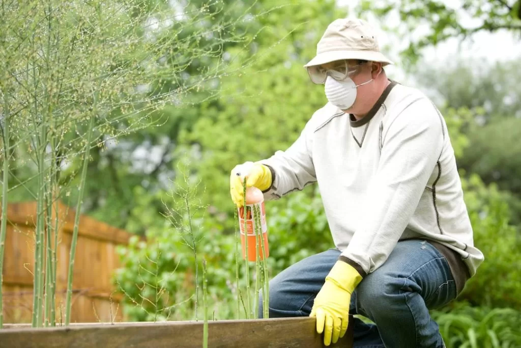 A pest control technician sprays preventative pesticide around the exterior of a home.