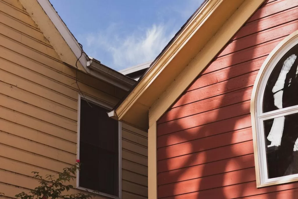 Home with red siding and yellow rain gutters that a local gutter company can clean and repair