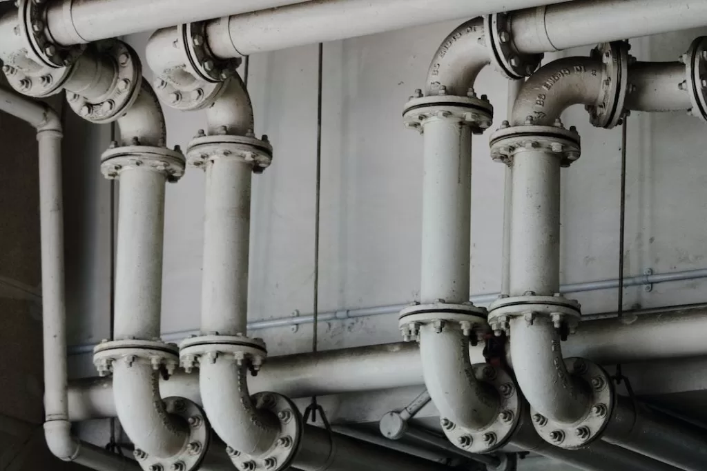 A system of white industrial pipes snaked around a vent.