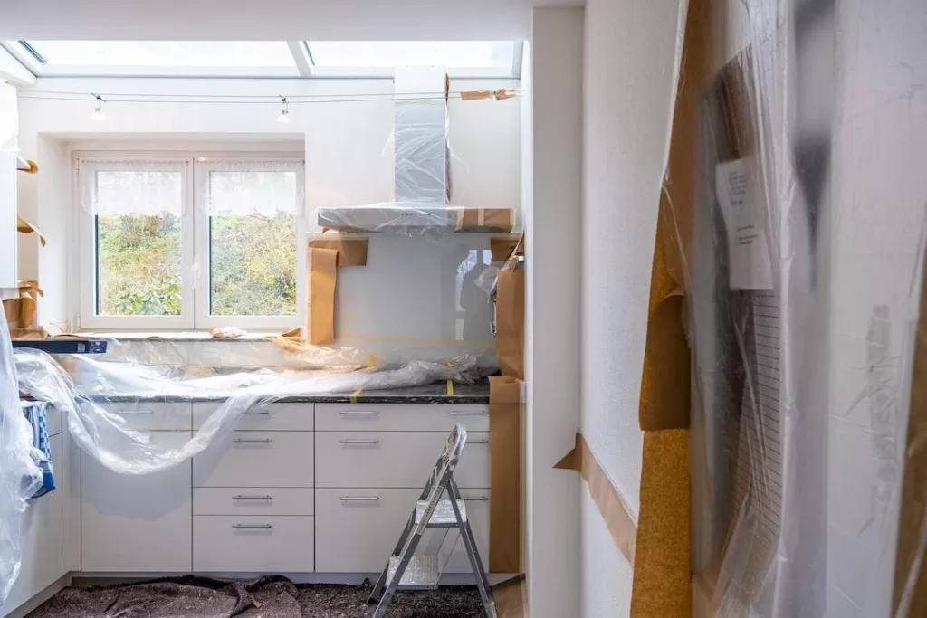 Kitchen in the middle of a remodel with plastic draped over countertops and a stepstool on the floor