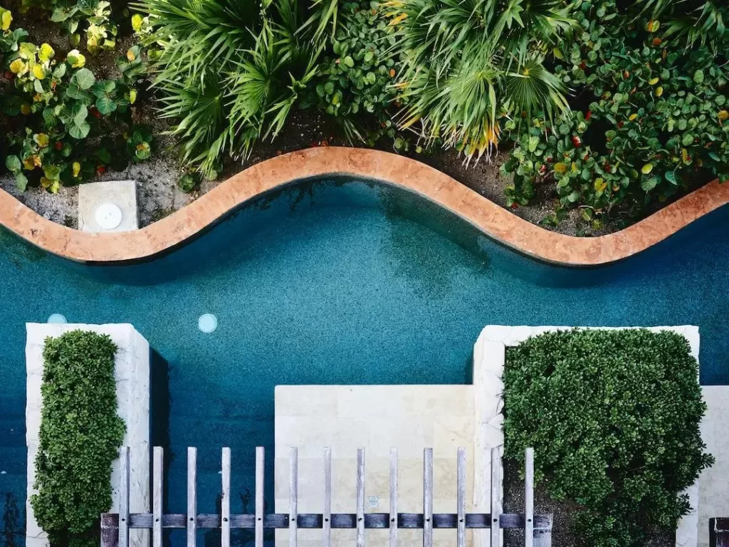 A top view of a backyard pool surrounded by landscaping to create a tropical feel.