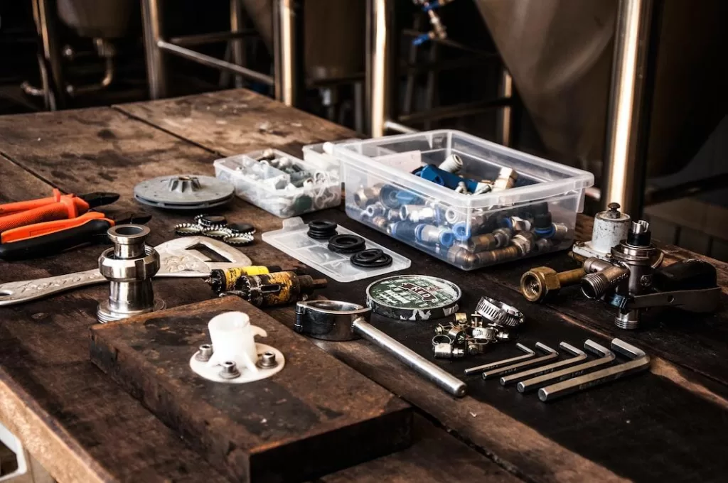 An array of plumbing tools and supplies are laid out on a wood table.