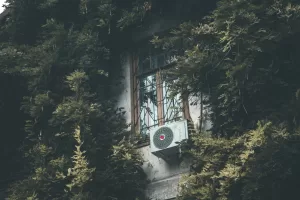Air conditioner on the background of a overgrown wall and window
