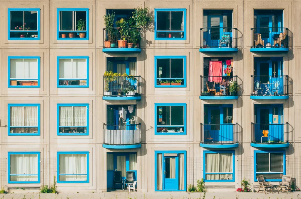 Facade of a modern apartment building with colorful balconies adorned with plants and laundry hanging to dry, showcasing everyday urban life