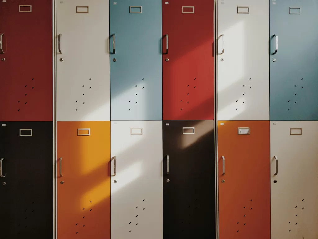 Colorful lockers in a row, featuring an array of colors including maroon, white, sky blue, and orange, casting soft shadows on their surfaces.